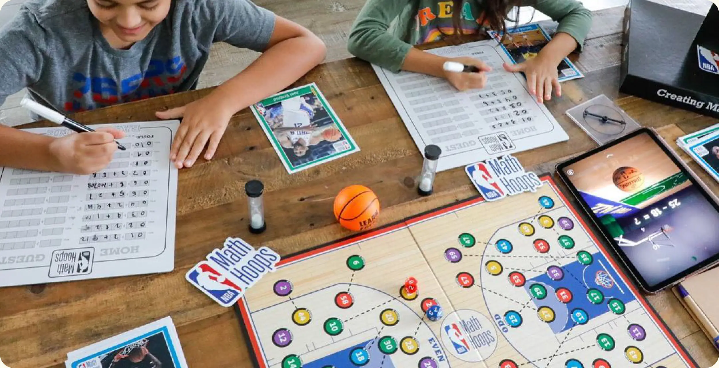 Two students playing the NBA Math Hoops board game with score sheets and player cards