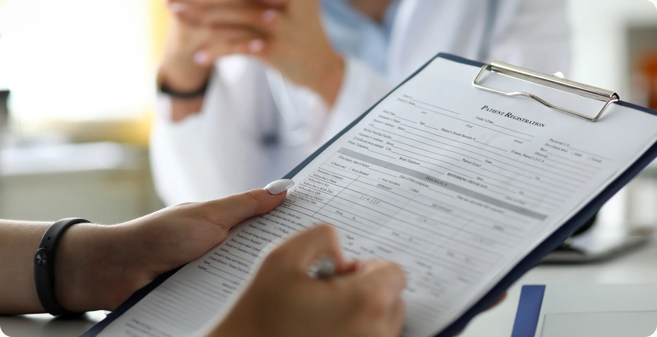 A patient filling in a paper registration form on a clipboard