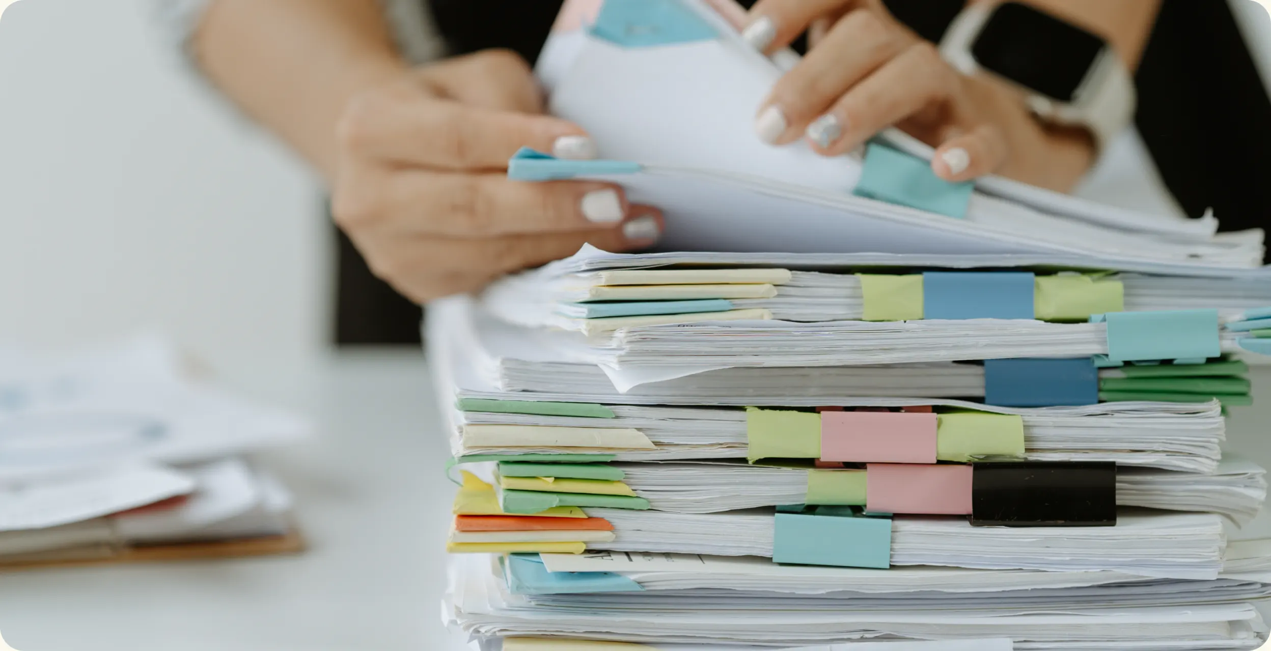 A tall stack of paper forms marked with colored tabs